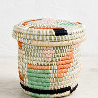 Flora Multi: A small, round lidded basket made from woven sweetgrass with geometric pastel pattern.