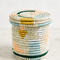 Pastel Multi: A small, round lidded basket made from woven sweetgrass with geometric pastel and metallic pattern.