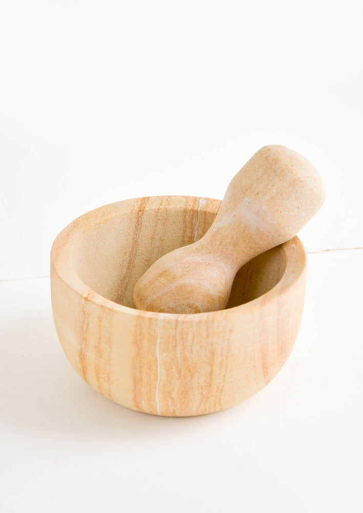 Large mortar and pestle with both pieces made from variegated tan-colored sandstone