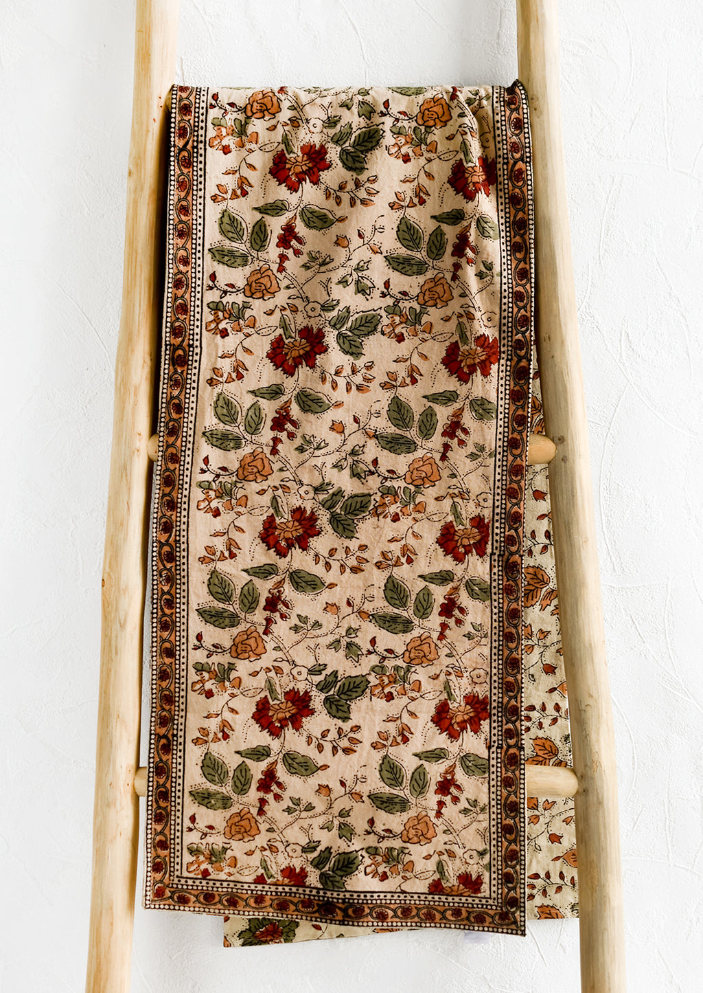1: A block printed table runner in crimson, green and beige floral print.