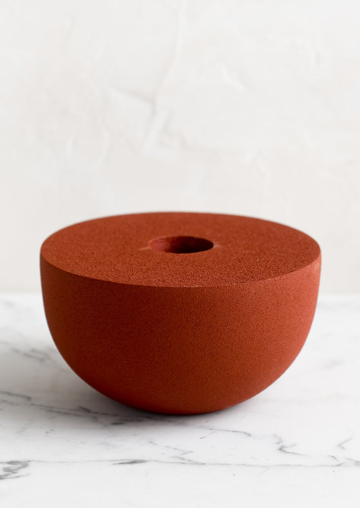 A red half-sphere taper holder in matte texture.