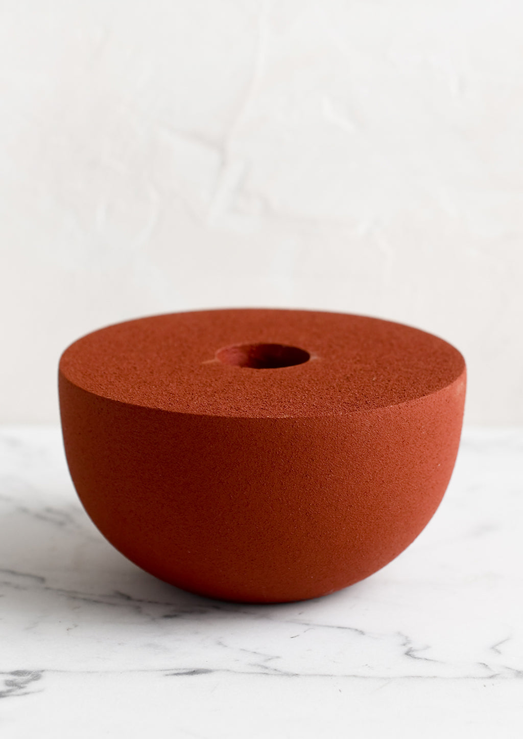 2: A red half-sphere taper holder in matte texture.