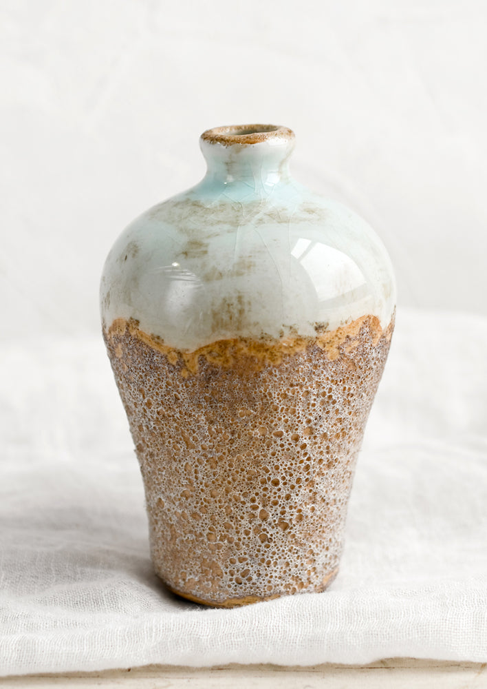 A bud vase in distressed seafoam and brown sandy glaze.