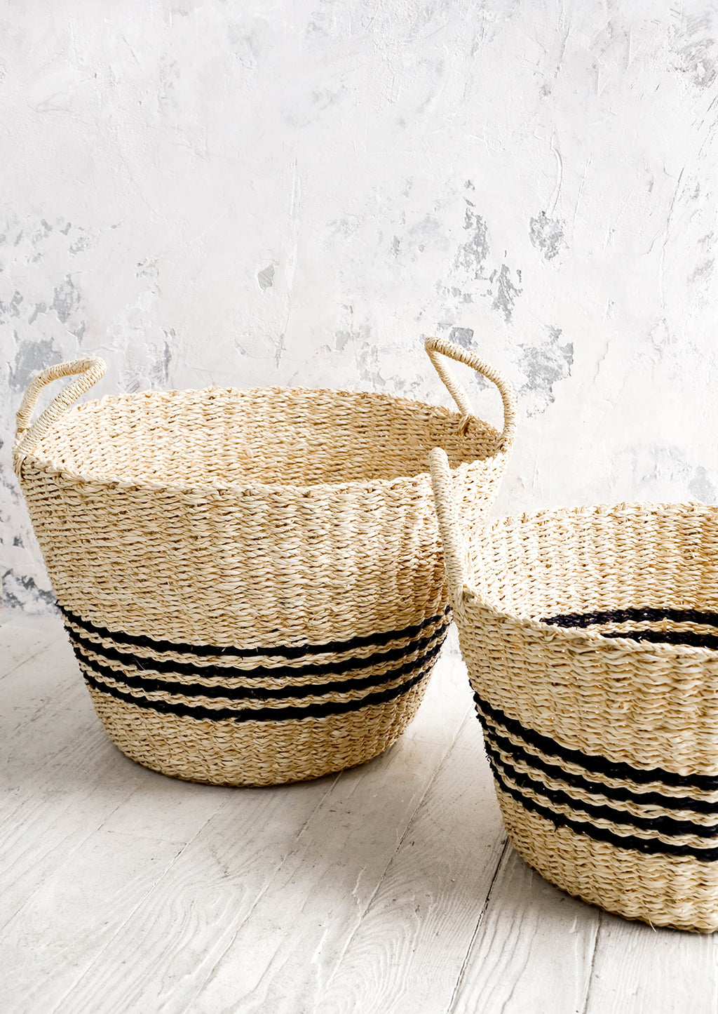 2: Round woven storage baskets with tapered bottom. Four black stripes printed at middle.