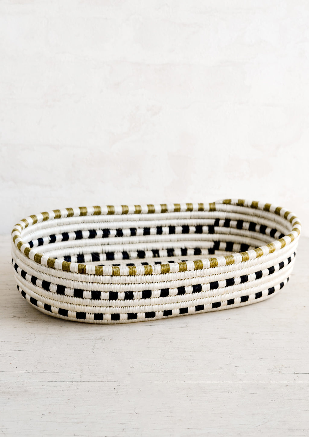 White / Black Multi: An oval shaped basket made from woven sweetgrass in black and white dash pattern.