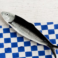Grey: A ceramic tray in the shape of a sardine in black and grey.