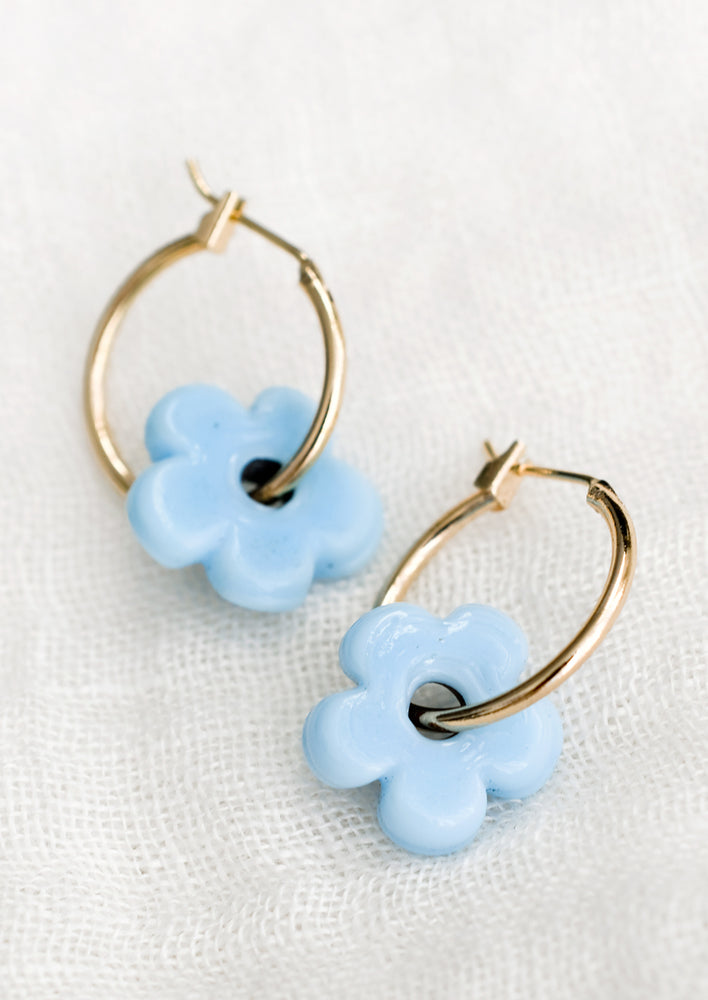 A pair of gold hoop earrings with single cyan flower bead.
