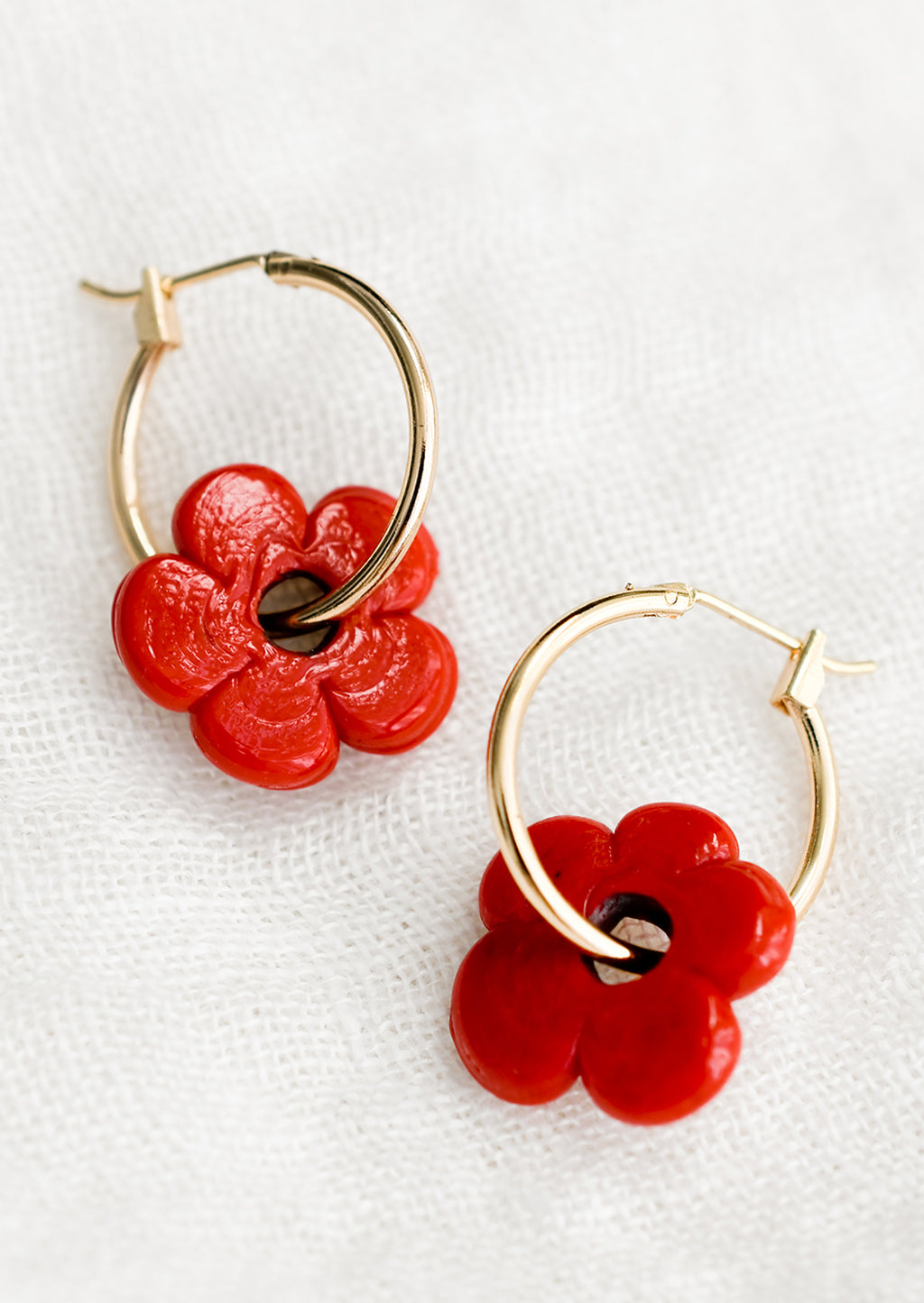 Cherry: A pair of gold hoop earrings with single red flower bead.