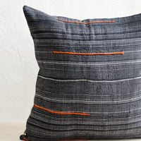 1: A square throw pillow made from dark blue fabric with grey stripes and embroidered orange lines.
