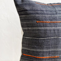 3: A square throw pillow made from dark blue fabric with grey stripes and embroidered orange lines.