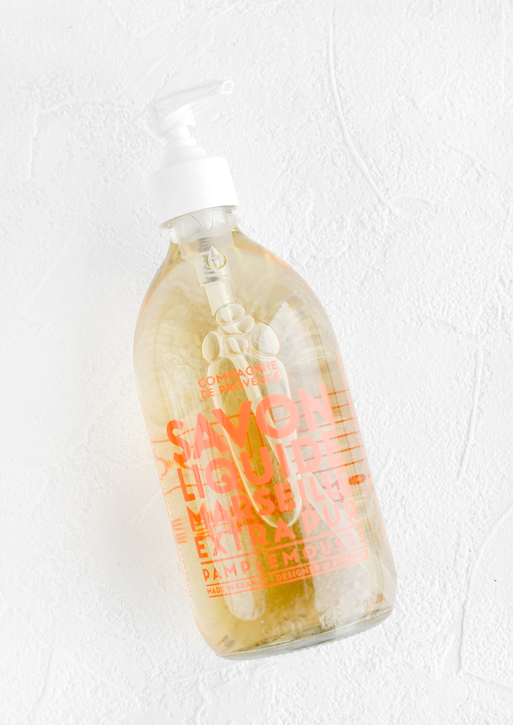 Grapefruit: A clear glass soap bottle with bold orange text printed on bottle