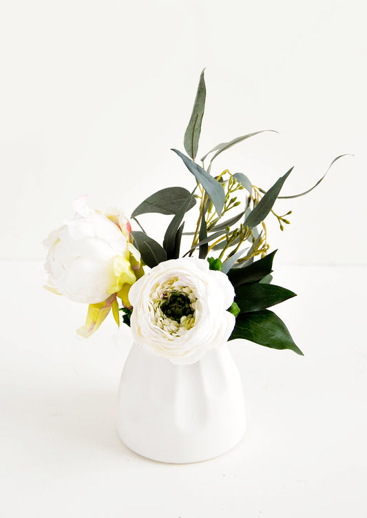 Small and round mini ceramic vase in white shown with floral arrangement