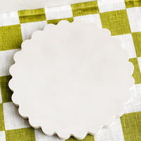 Cream: A concrete trivet with scalloped edges in cream.