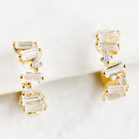 1: A pair of gold and crystal huggie hoop earrings with clear baguettes.
