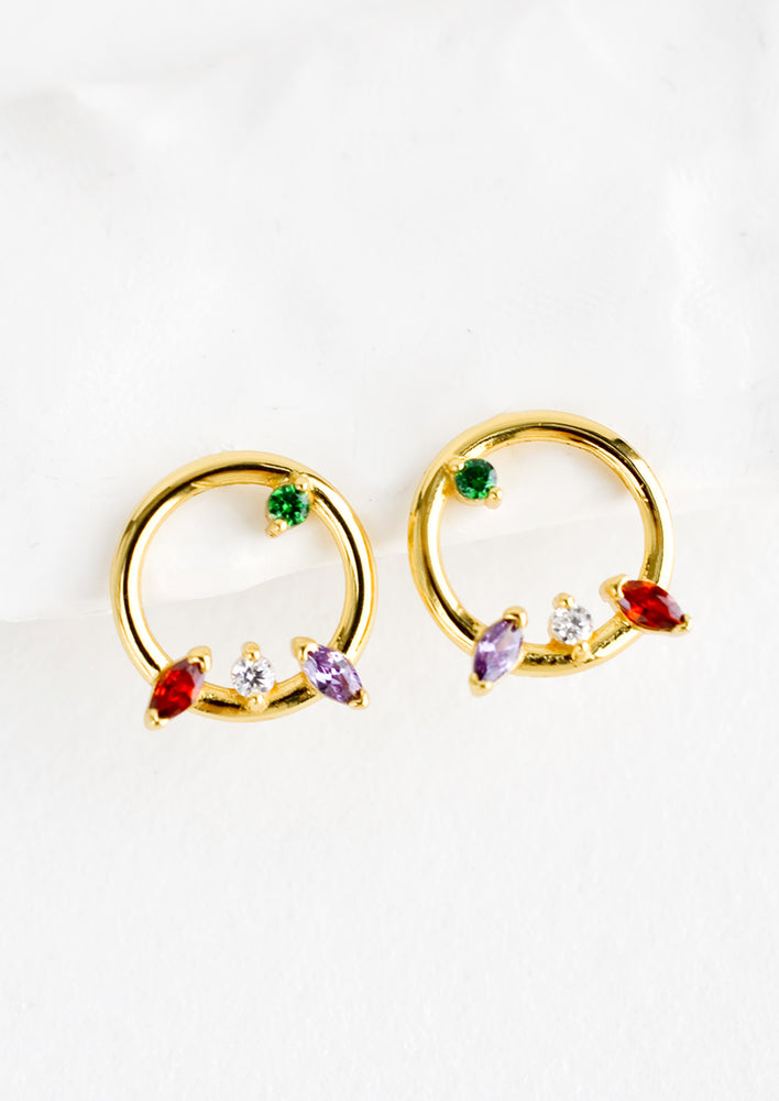 1: A pair of gold stud earrings in the shape of a circle with randomized colored crystal detailing.
