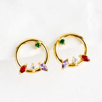 1: A pair of gold stud earrings in the shape of a circle with randomized colored crystal detailing.