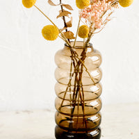 1: A clear brown glass vase in a curvy silhouette with pink and yellow flowers.