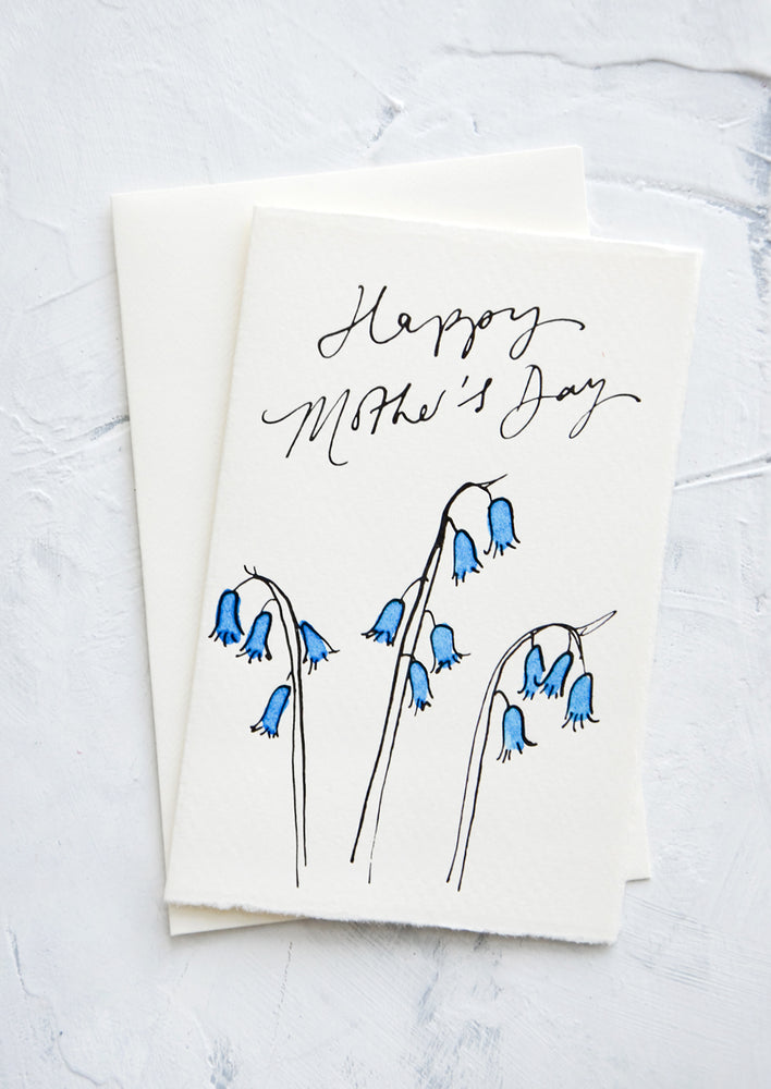 1: A letterpress printed greeting card made from hand-torn paper with image of bluebells and cursive text reading "Happy Mother's Day".
