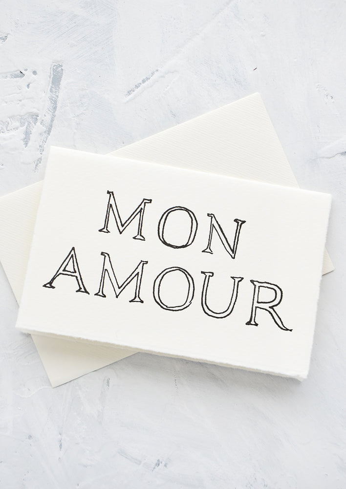 A letterpress printed greeting card on handmade paper with "Mon Amour" printed on front.