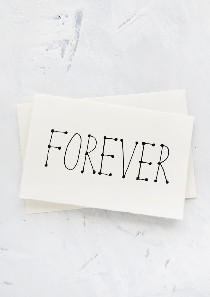 A letterpress printed greeting card made from handmade paper with "FOREVER" printed in black letters