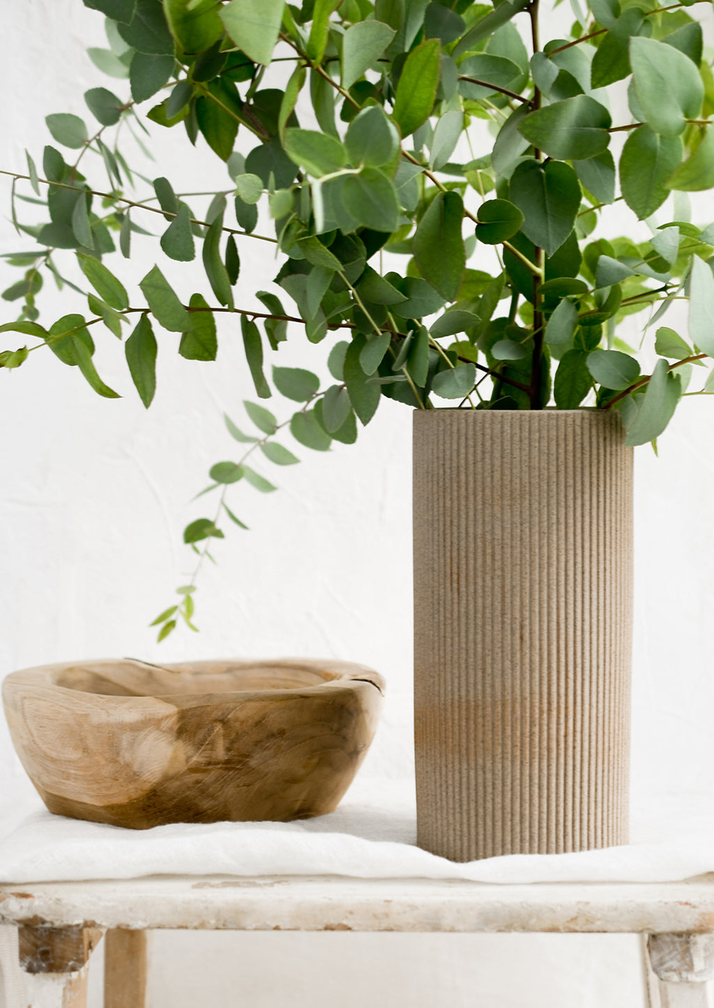 3: Eucalyptus in a sandy brown vase with wooden bowl.