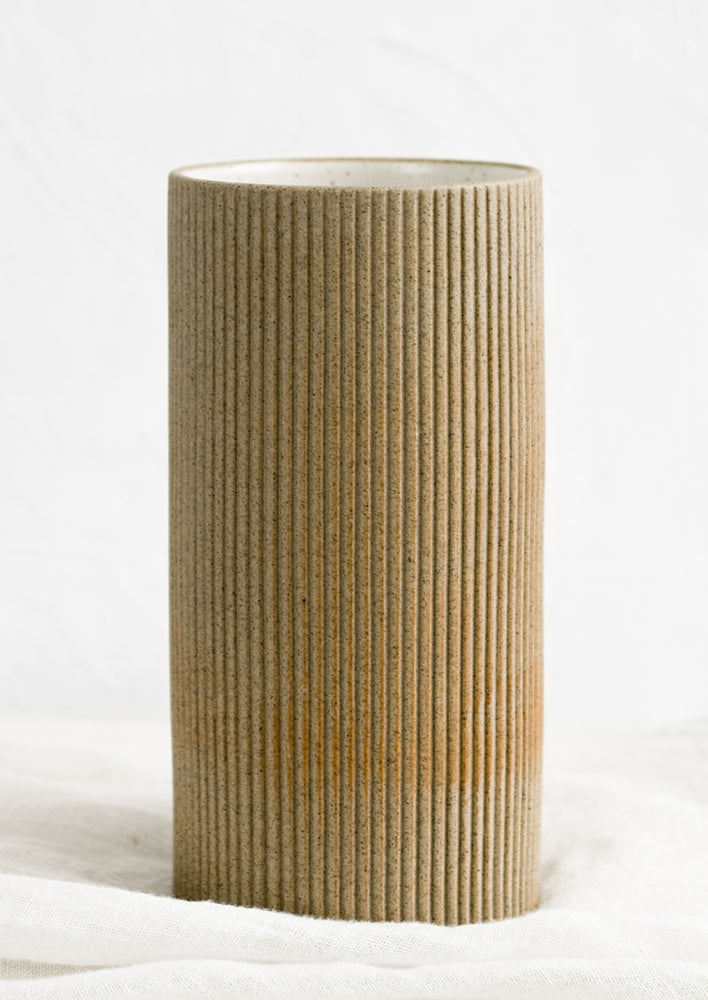 A sand brown cylindrical ceramic vase.