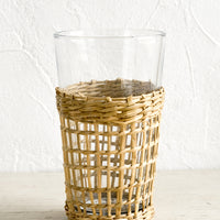1: A tall glass cup wrapped in decorative seagrass cage.