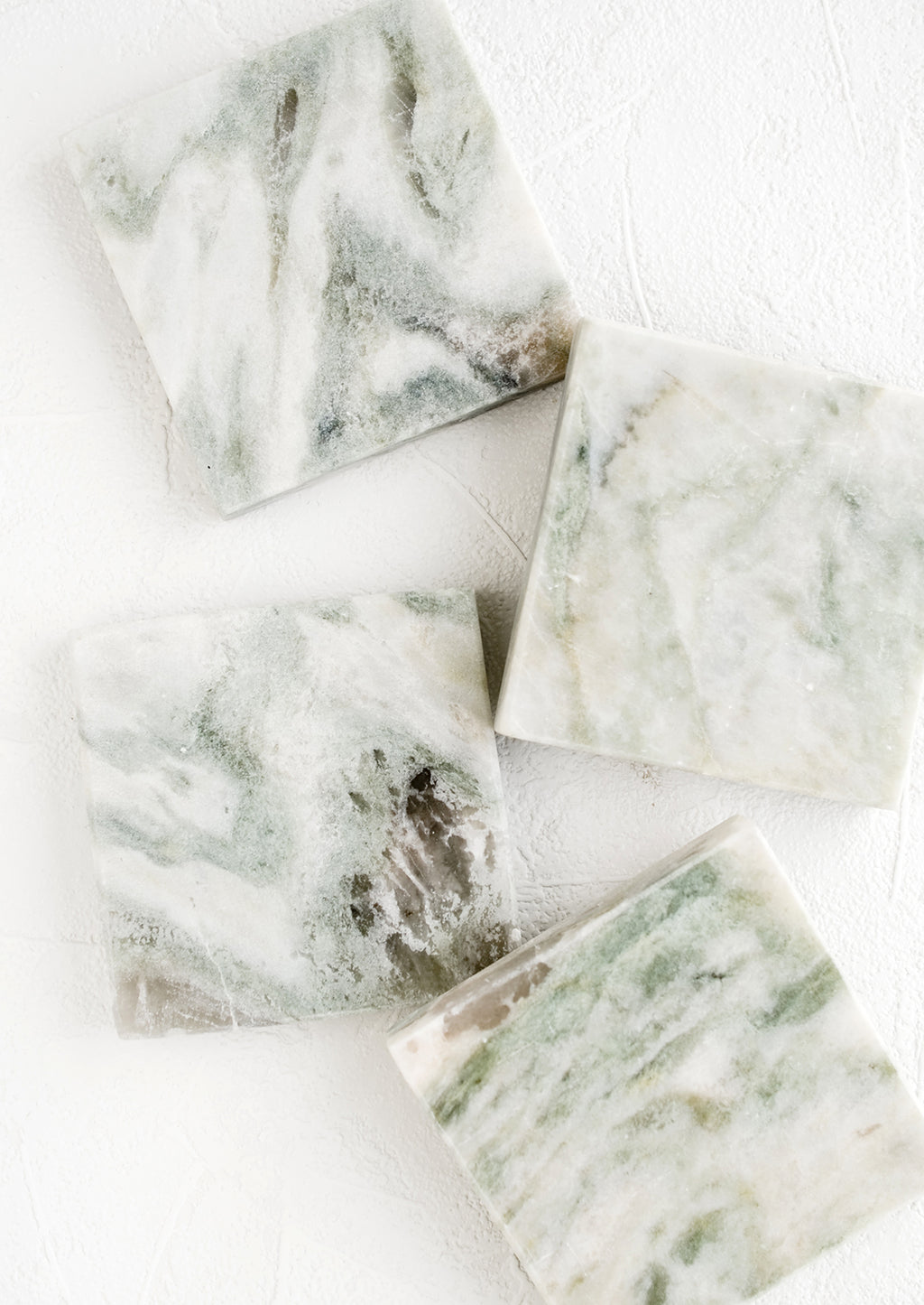 1: Four square marble coasters with variegated tones of green, white and grey.