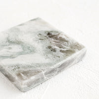 2: A thick marble coaster in variegated tones of green, grey and white.