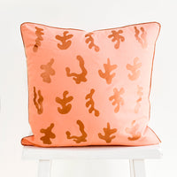 3: Square throw pillow in peach color with copper, screen printed seaweed shapes and copper trim
