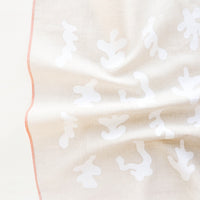 1: A crumpled beige towel with white squiggle pattern and orange trim.