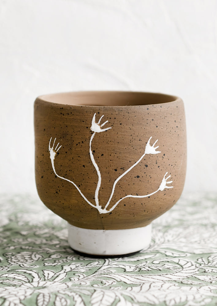 1: A small natural clay pot with white seaweed pattern.