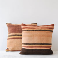 2: Two square kilim pillows with rust, adobe, and brown stripes. 