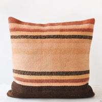 1: A striped kilim pillow in rust, adobe, and brown.