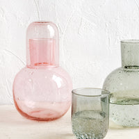 1: Translucent glass drinking carafes in pink and grey.