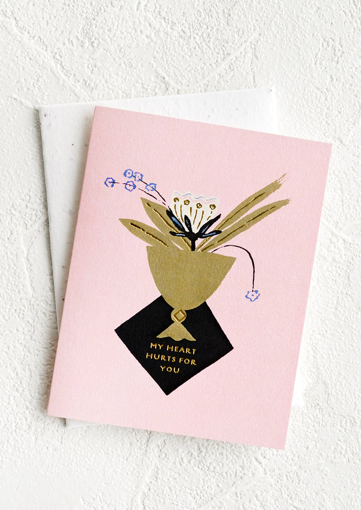 Pink greeting card with image at center of floral arrangement in vase, small gold text below reads "My Heart Hurts For You".