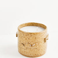 Santal: A candle in a light brown speckled ceramic container featuring three dimensional squiggles on its surface.