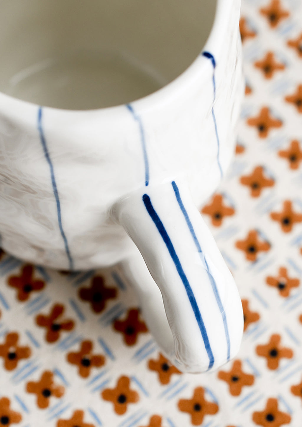 1: A pinched white mug with vertical thin blue stripes.