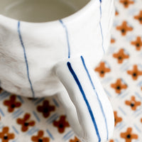 1: A pinched white mug with vertical thin blue stripes.