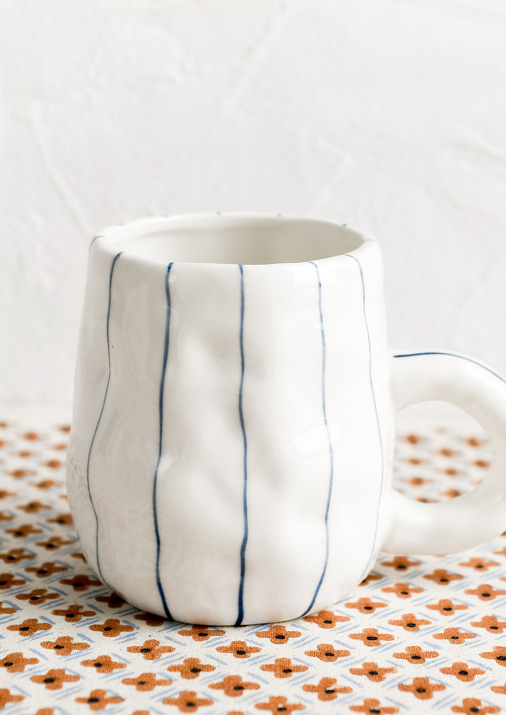 3: A pinched white mug with vertical thin blue stripes.