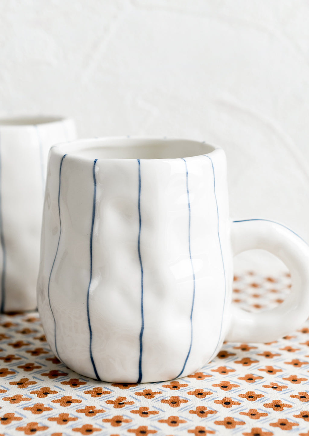2: A pinched white mug with vertical thin blue stripes.