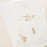 1: A greeting card made from handmade flower paper with gold script on front that reads "Sending You Love".