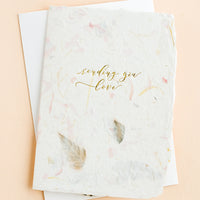 3: A greeting card made from handmade flower paper with gold script on front that reads "Sending You Love".