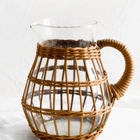 1: A round glass pitcher with sepia hued cage.