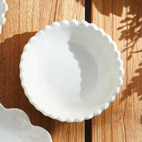 2: A small ceramic bowl with scalloped rim in white.