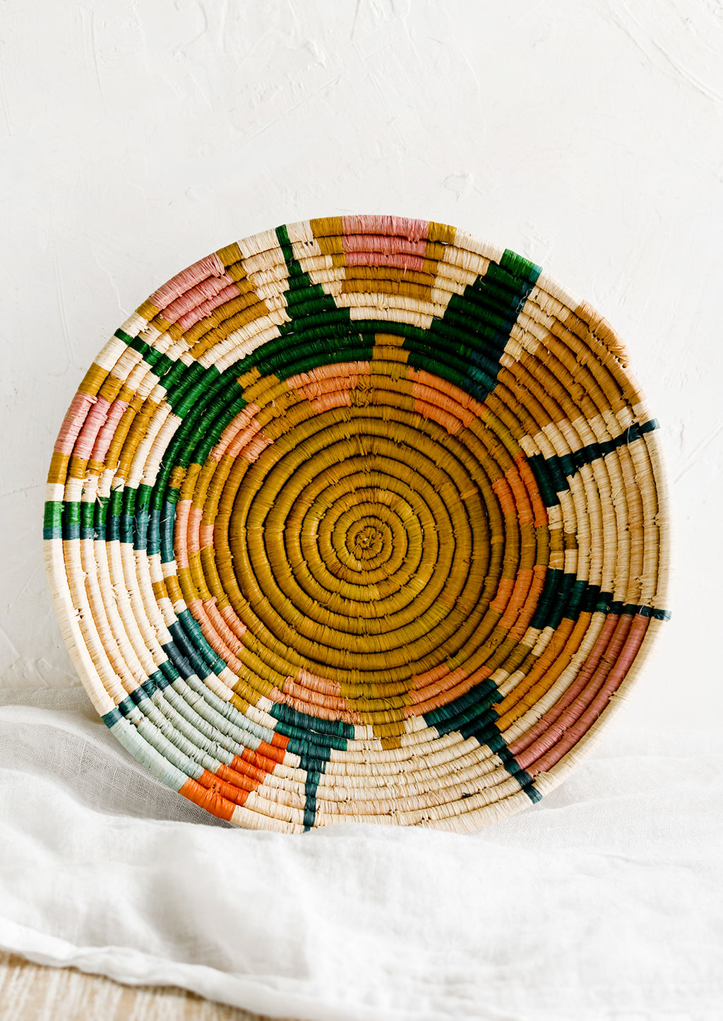 1: A woven raffia bowl with sunburst pattern.