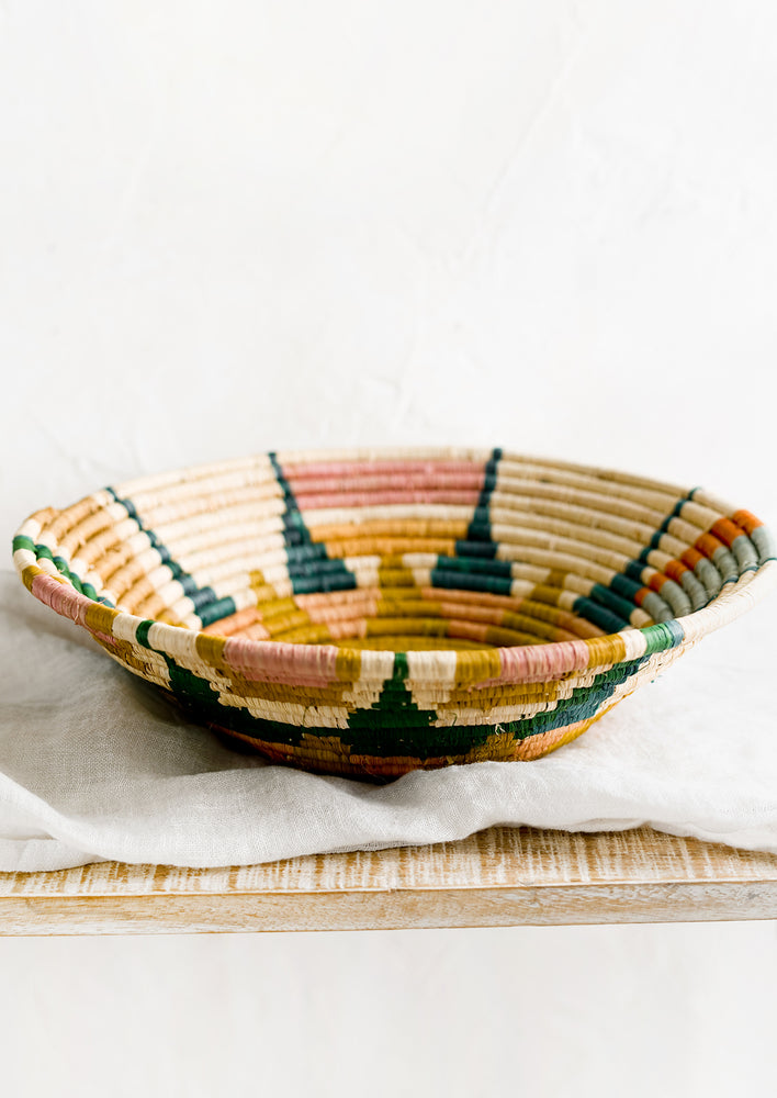 A woven raffia bowl with sunburst pattern.
