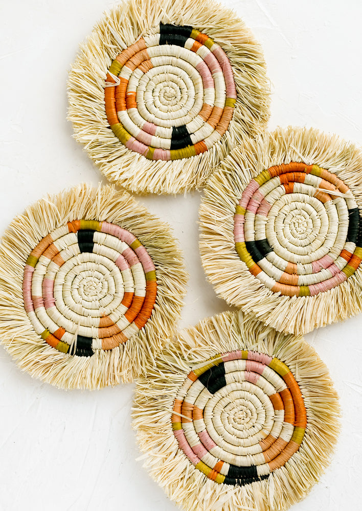 A set of four raffia coasters with color and fringe detail.