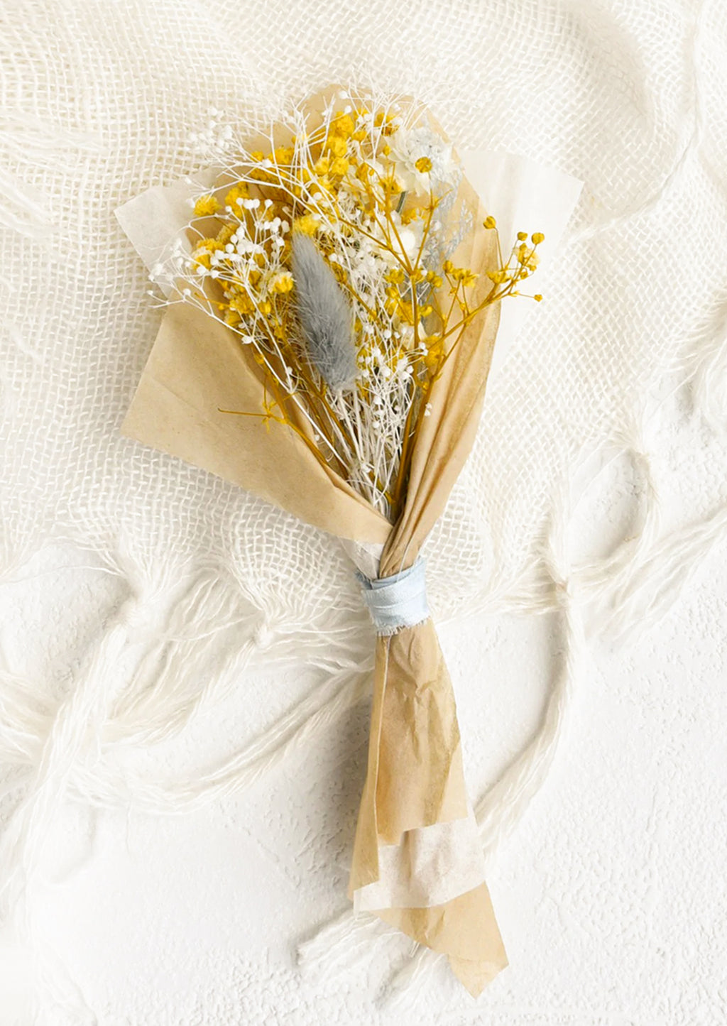 Mini: A small bouquet of dried yellow, white and light blue flowers wrapped in parchment paper