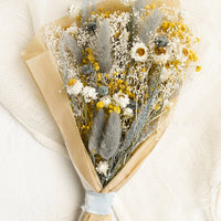 Full Size: A large bouquet of dried yellow, white and light blue flowers wrapped in parchment paper
